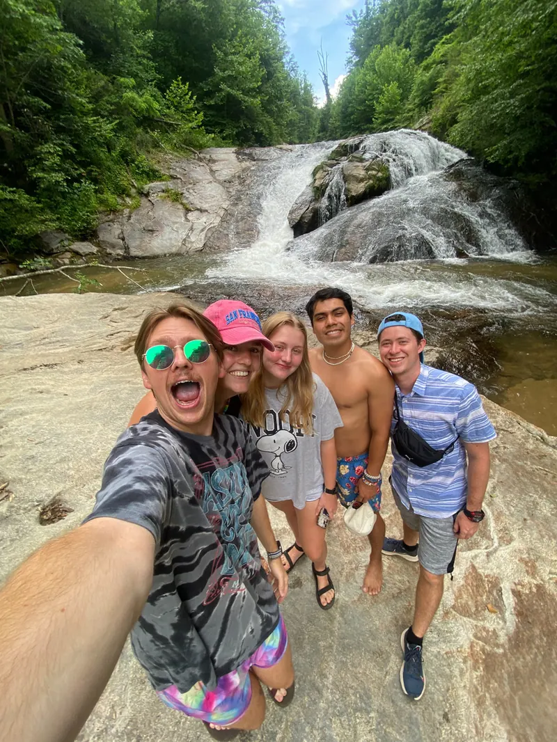 Grupo de amigos tomándose una selfie frente a una cascada