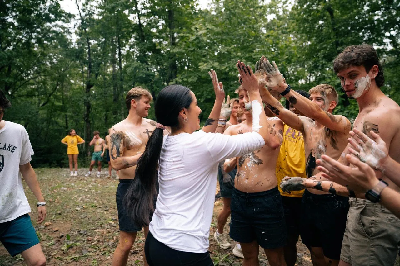 Counselors chocando las manos, pintados de colores, en un campamento de verano