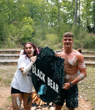 Dos counselors posando con un letrero del equipo Black Bear