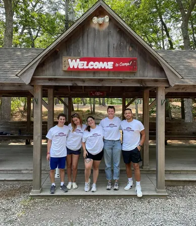 Cinco counselors frente a la entrada del campamento